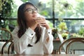 young woman holding mobile phone thinking and waiting for someone in coffee cafe. image for business,people,portrait,mobile and t Royalty Free Stock Photo