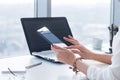 Young woman holding modern tablet computer, using device at workplace during break, chatting, blogging and posting