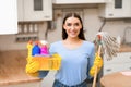 Young woman holding mop and bucket with detergents