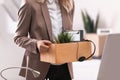 Young woman holding moving box with office stuff indoors Royalty Free Stock Photo