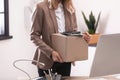 Young woman holding moving box with office stuff indoors Royalty Free Stock Photo