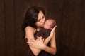 Young woman holding a newborn baby in her arms on the white background. Newborn photosession. Family portrait. Mother is kissing h Royalty Free Stock Photo