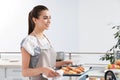 Young woman holding oven sheet with homemade croissants in kitchen