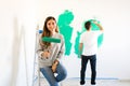 Young woman holding a paint roller with her partner painting Royalty Free Stock Photo