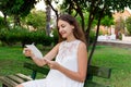 Young woman is holding a pen and a notepad and checking her schedule, ideas and thoughts posing outdoors