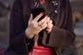 Young woman holding phone in hands with beautiful red manicure. Close up picture outdoor Royalty Free Stock Photo