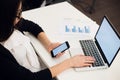 Young woman holding a phone. Workplace near the window with laptop. Close up Royalty Free Stock Photo