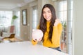 Young woman holding piggy bank screaming proud and celebrating victory and success very excited, cheering emotion Royalty Free Stock Photo