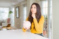 Young woman holding piggy bank serious face thinking about question, very confused idea Royalty Free Stock Photo