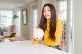 Young woman holding piggy bank very happy and excited, winner expression celebrating victory screaming with big smile and raised Royalty Free Stock Photo