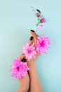 Young woman holding pink flowers in hands on blue background. Minimal flat lay spa concept Royalty Free Stock Photo