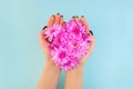 Young woman holding pink flowers in hands on blue background. Beautiful florist heart shape love concept Royalty Free Stock Photo