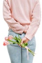 Young woman holding of pink tulips behind her back on a white background. Royalty Free Stock Photo