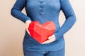 Woman holding polygonal diamond shaped red heart in front of her body