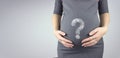 Young woman holding pregnant belly in hands with hologram question mark.. Pregnancy, maternity concept Royalty Free Stock Photo