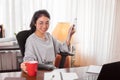 Young woman holding red coffee cup and using tablet for work at home Royalty Free Stock Photo