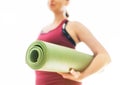 Young Woman holding rolled gymnastic yoga rubber mat on the white background light starting morning yoga exercises. Active people