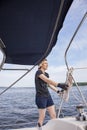 Woman sailing holding ropes to adjust sails on sailboat Royalty Free Stock Photo