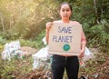 The young woman holding `Save the planet` Poster showing a sign protesting against plastic pollution in the forest. The concept of Royalty Free Stock Photo
