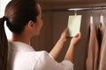 Young woman holding scented sachet in wardrobe