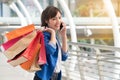 Young woman holding shopping bags and talking cell phone walking on shopping street background. Lifestyle shopping Royalty Free Stock Photo