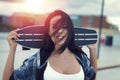 Young woman holding skateboard in sunset portrait