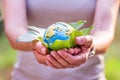 Young woman holding small planet in hands against spring or summer green background. Ecology, environment and Earth day Royalty Free Stock Photo