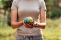 Young woman holding small planet in hands against spring or summer green background. Ecology, environment and Earth day Royalty Free Stock Photo