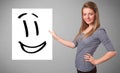 Young woman holding smiley face drawing