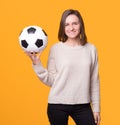 Young woman is holding a soccer football ball over yellow background. Royalty Free Stock Photo