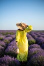 Young woman holding straw basket with lavender flowers standing on the lavender field. Girl dressed in a yellow dress and a straw Royalty Free Stock Photo