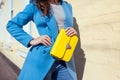 Young woman holding stylish handbag and wearing trendy blue coat. Spring female clothes and accessories. Fashion