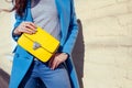 Young woman holding stylish handbag and wearing trendy blue coat. Spring female clothes and accessories. Fashion