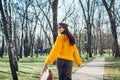 Young woman holding stylish handbag and wearing yellow sweater. Spring female clothes and accessories. Fashion