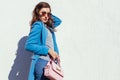 Young woman holding stylish handbag and wearing trendy blue coat. Spring female clothes and accessories. Fashion