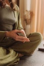 Young Woman holding Tarot cards and sitting in lotus pose on yoga mat, relaxed with closed eyes. Mindful meditation concept.