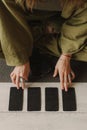 Young Woman holding Tarot cards and sitting in lotus pose on yoga mat, relaxed with closed eyes. Mindful meditation concept.