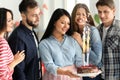 Young woman holding tasty cake with firework candles and her friends at birthday party indoors Royalty Free Stock Photo