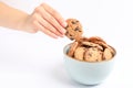 Young woman holding tasty chocolate chip cookie over bowl on white background Royalty Free Stock Photo