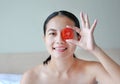 Young woman holding tomato slices on her eye, concept for skin care Royalty Free Stock Photo