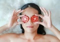 Young woman holding tomato slices on her eye, concept for skin care Royalty Free Stock Photo