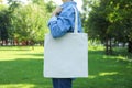 Young woman holding tote bag against greenery background Royalty Free Stock Photo