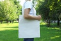 Young woman holding tote bag against greenery background Royalty Free Stock Photo