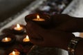 Young woman holding traditional ceramic bowl with candle light in hands. Be the light concept. On candles lights background. Royalty Free Stock Photo