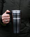 Young woman holding travel Tumbler stainless Steel mug with hot drink, reusable Insulated Flask on winter day, . Refuse, reduce,