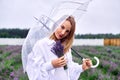 Pretty woman holding umbrella on stormy weather, standing in open field, checking rain. shallow depth of field photo Royalty Free Stock Photo