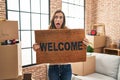 Young woman holding welcome doormat at new home afraid and shocked with surprise and amazed expression, fear and excited face Royalty Free Stock Photo