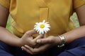 Young woman holding a white daisy flower in hand, cross-legged in yoga or prayer pose gesture. Be balance, find balance in life. Royalty Free Stock Photo