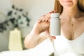 A young woman is holding mock up a white jar of vitamins or pills. Place for your logo Royalty Free Stock Photo