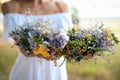 Young woman holding wreath made of beautiful flowers outdoors on sunny day, closeup Royalty Free Stock Photo